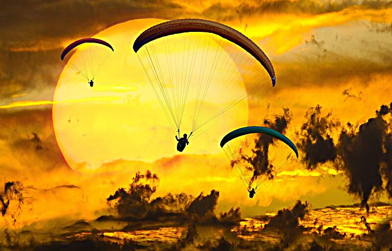 Paragliders Three paragliders set against sunset